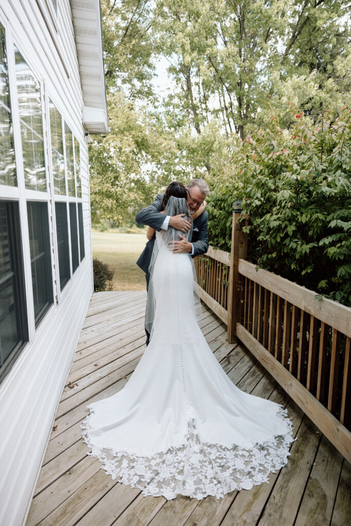 Bride hugs father before wedding ceremony outside