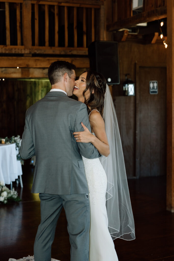 Bride laughs in groom's arms during first dance at wedding