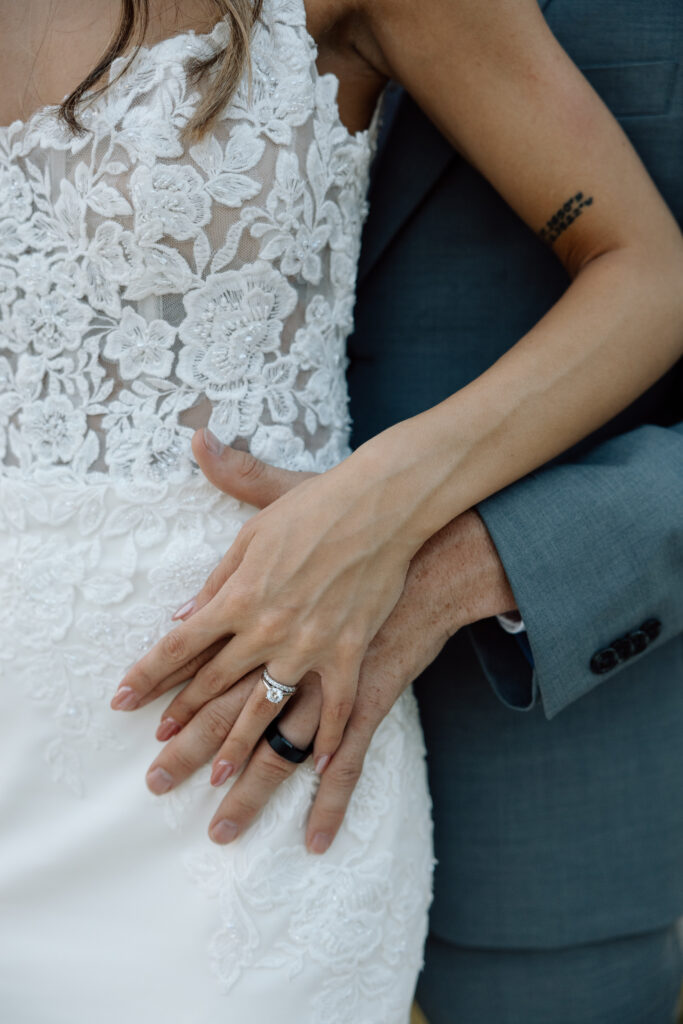 Couple lock hands and show rings after wedding ceremony