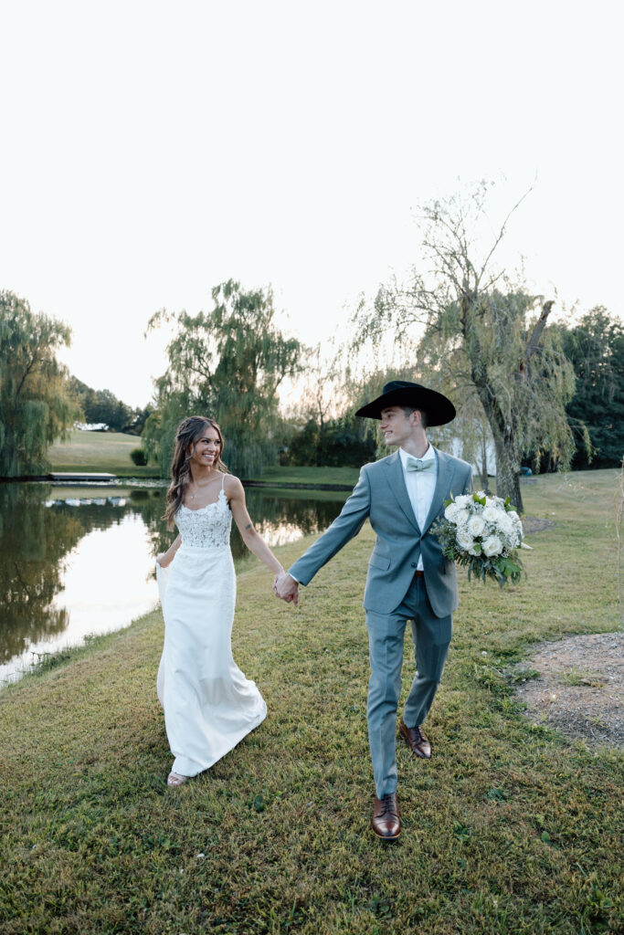 Bride and groom hold hands next to Pennsylvania lake