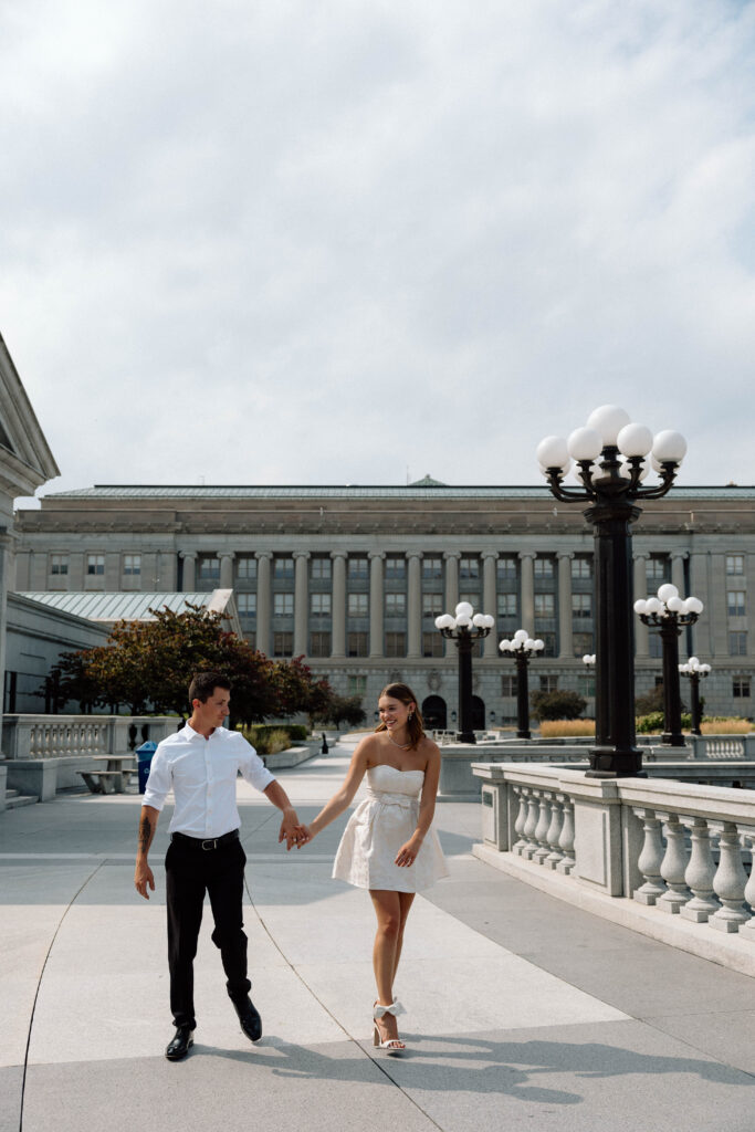 Couple hold hands and walk outside Pennsylvania State Capitol building