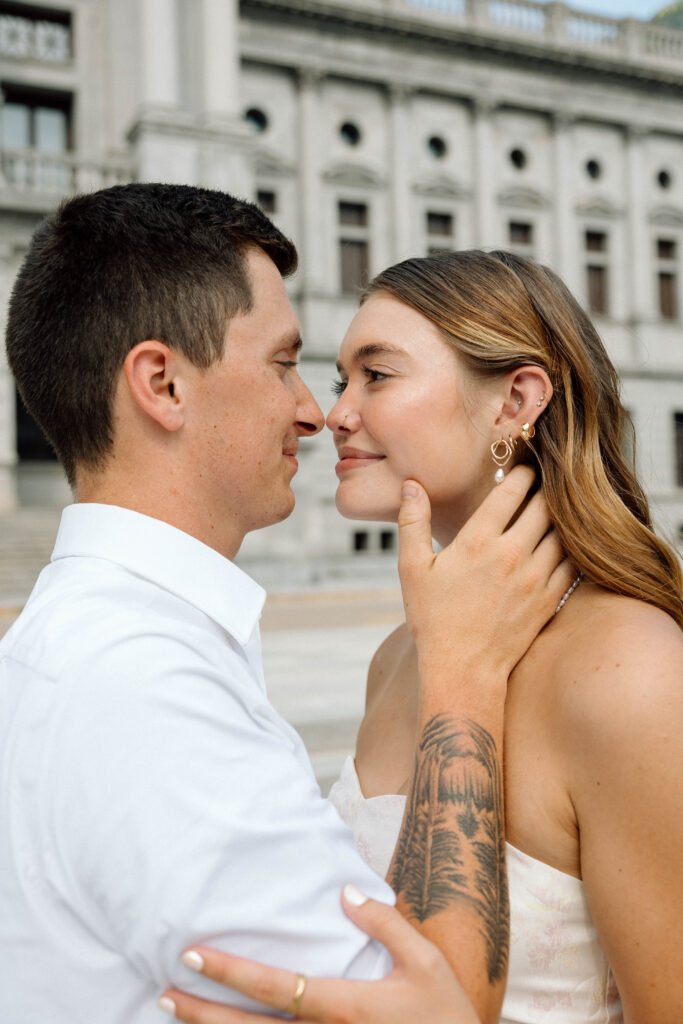 Couple smile and lean in for a kiss at their engagement luxury engagement photos