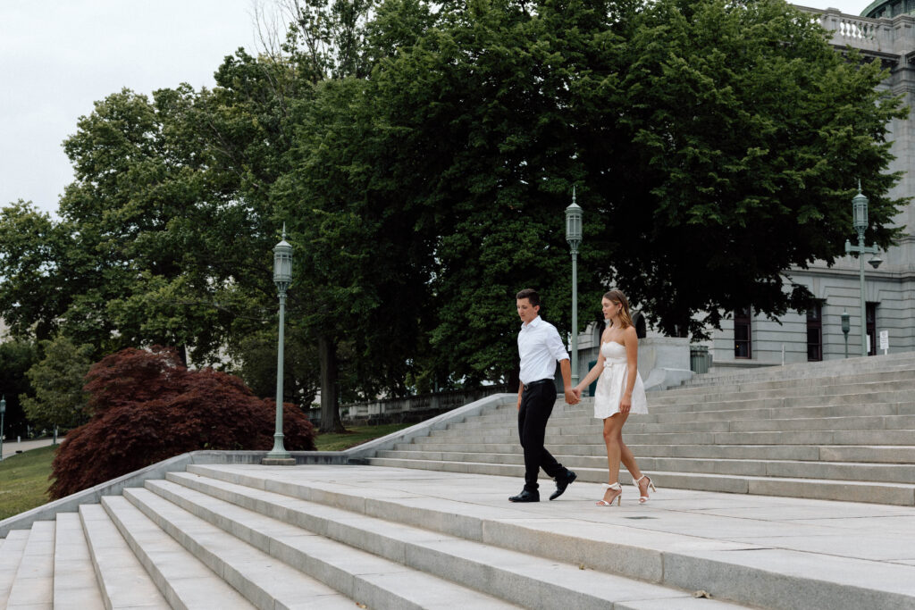 Couple hold hands and walk down the grand steps of the Pennsylvania Capitol