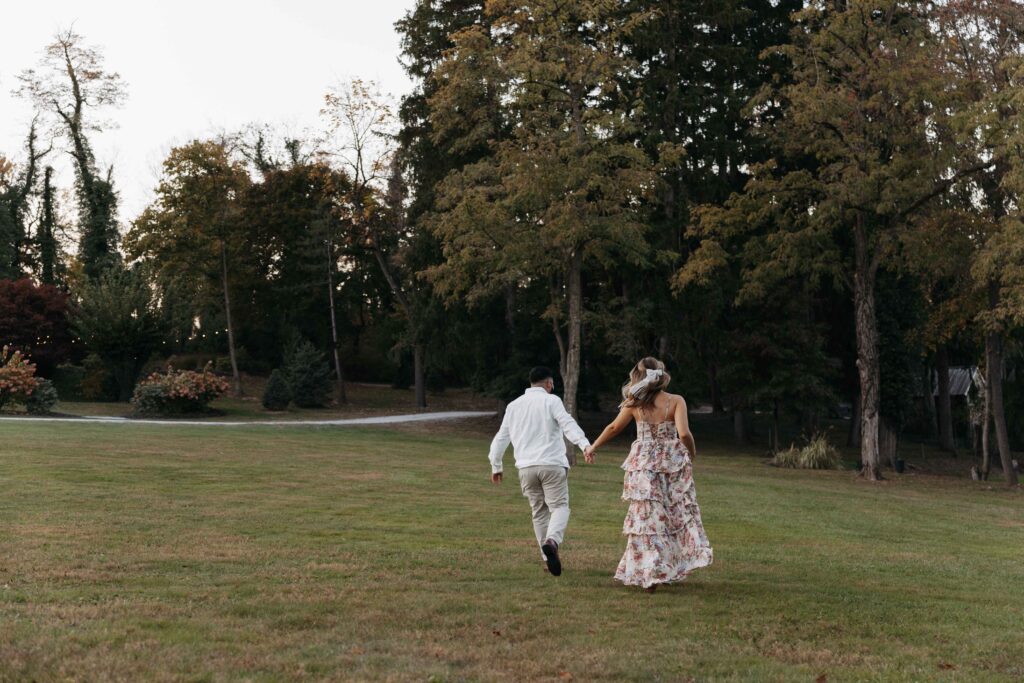 An engaged couple running through a field during their engagement session at Historic Shady Lane.