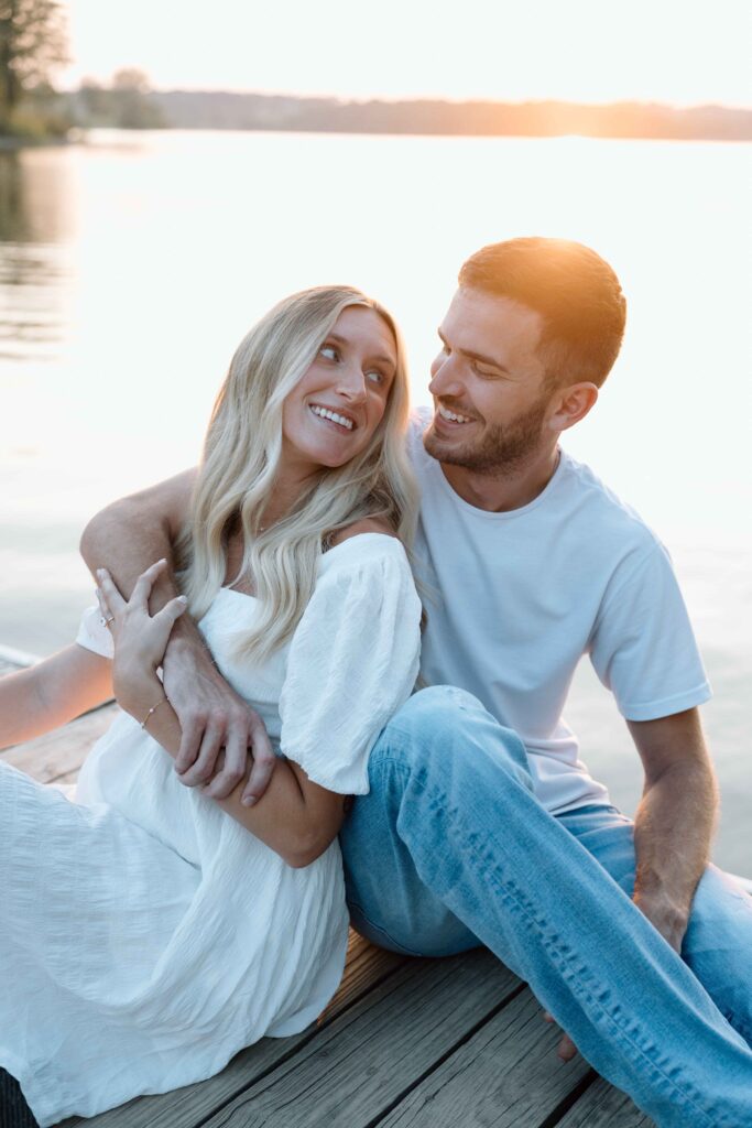 Couple sitting on a dock looking into each others eyes and smiling at Cordorus State Park during their photoshoot.