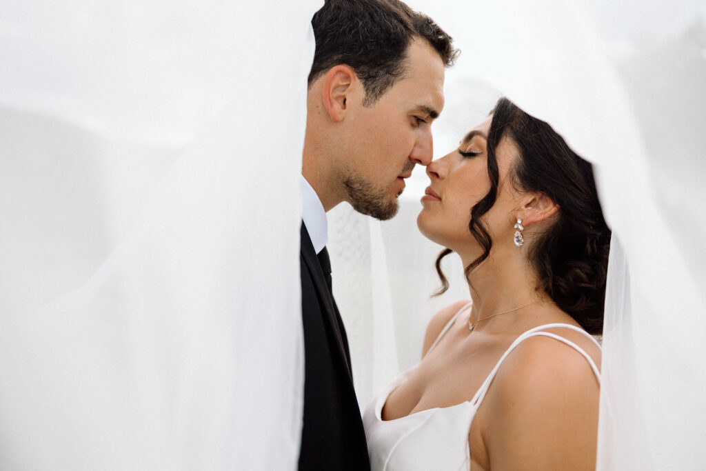 Bride and groom under the brides veil during their luxury wedding photoshoot.