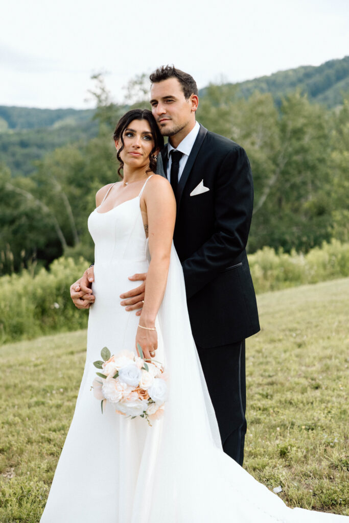 A newlywed couple looking off into the distance during their luxury wedding photoshoot in the mountains.