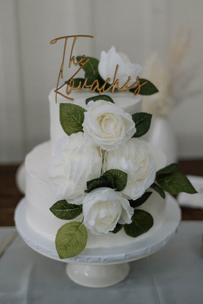 A simple wedding cake as a wedding budget idea. The cake is small and simple with white and green florals.