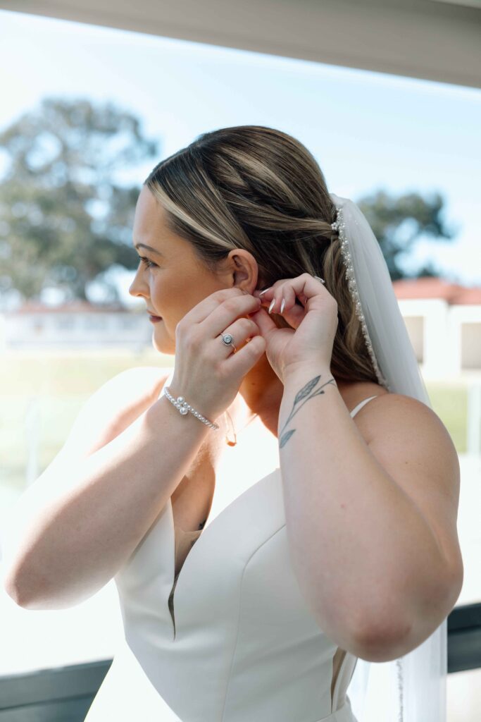 Bride getting ready for her wedding in San Diego and putting on earrings.