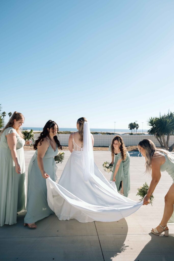 Bridesmaids fixing the trail on the brides wedding dress.