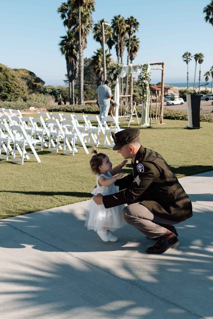 Groom picking up his daughter during their first look at his wedding in San Diego.