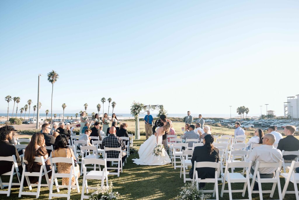 Destination wedding photographer captures intimate wedding wedding in San Diego. The bride and groom are kissing in the aisle. 