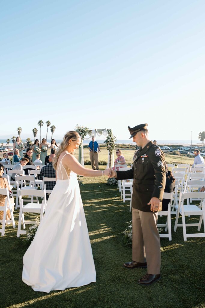 Bride and groom playing thumb wrestle at the end of the aisle at their wedding in San Diego