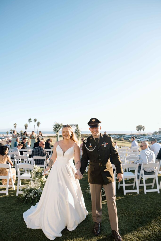 Bride and groom walking down the aisle smiling after getting married.