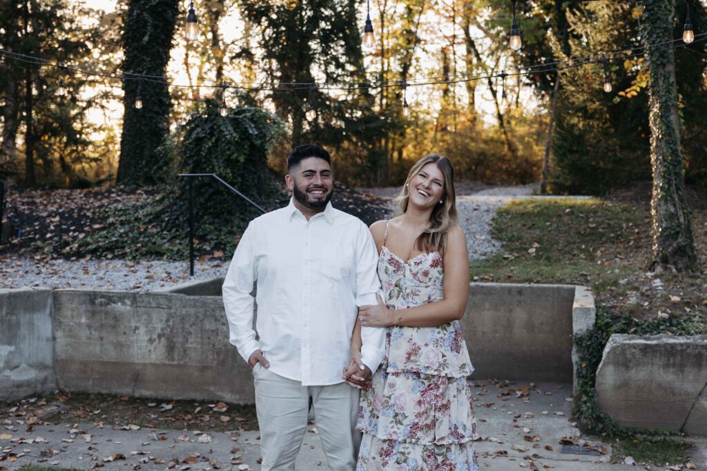 A fiancee holding her fiance's arm and smiling.