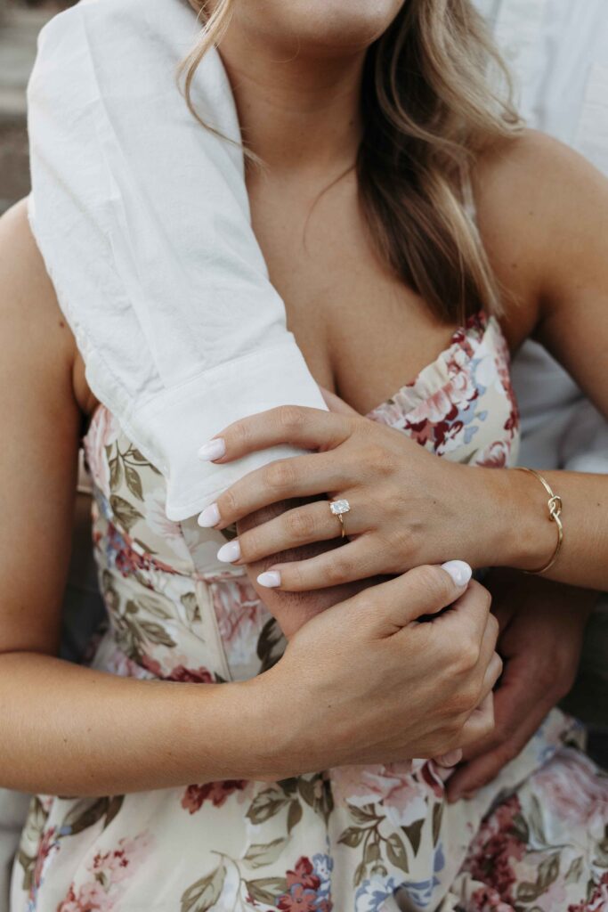 A close up of a woman with her fiances arm around her. 