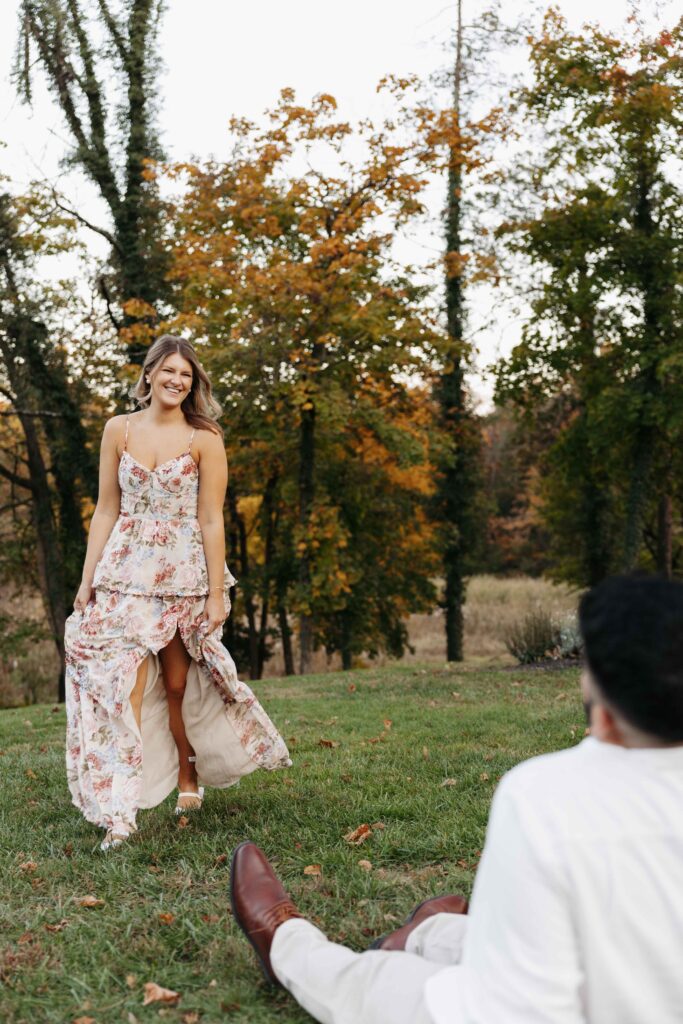 A woman dancing around in the grass for her fiance. 