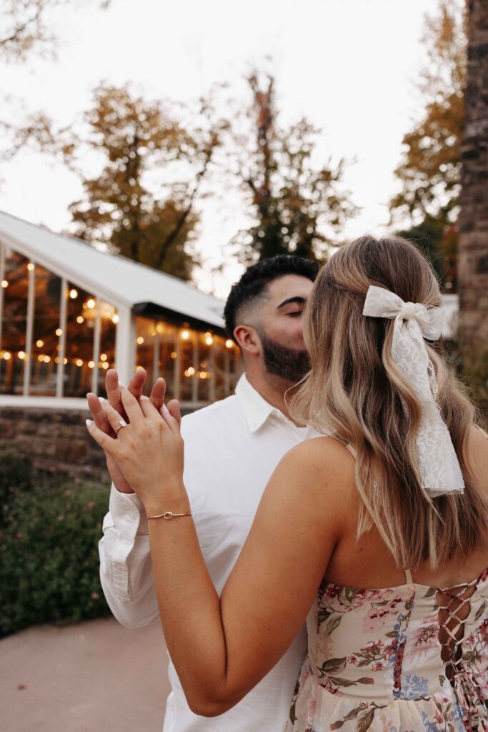 A close up of a couple holding hands and slow dancing. 