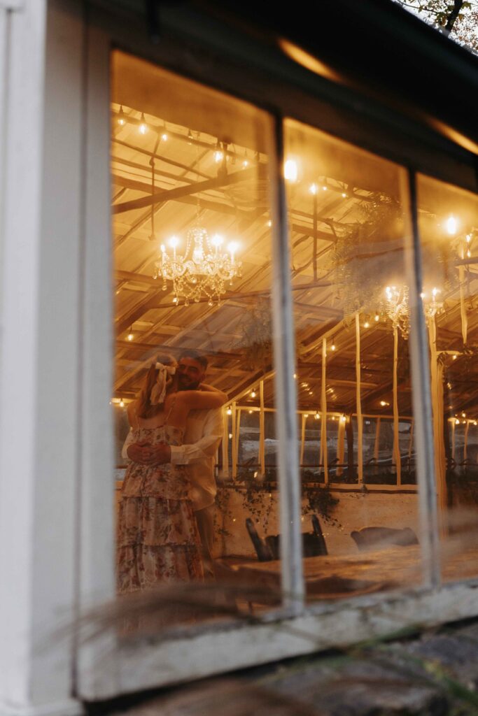 Couple hugging as they dance in the greenhouse.