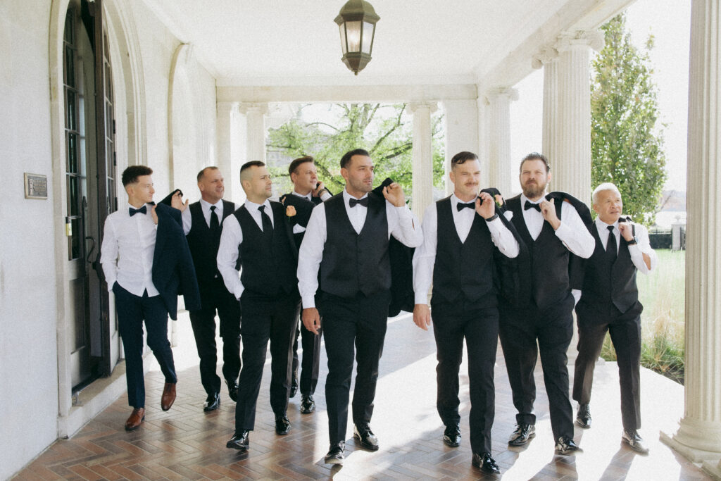 Groom and his groomsmen walking and looking into the distance. 