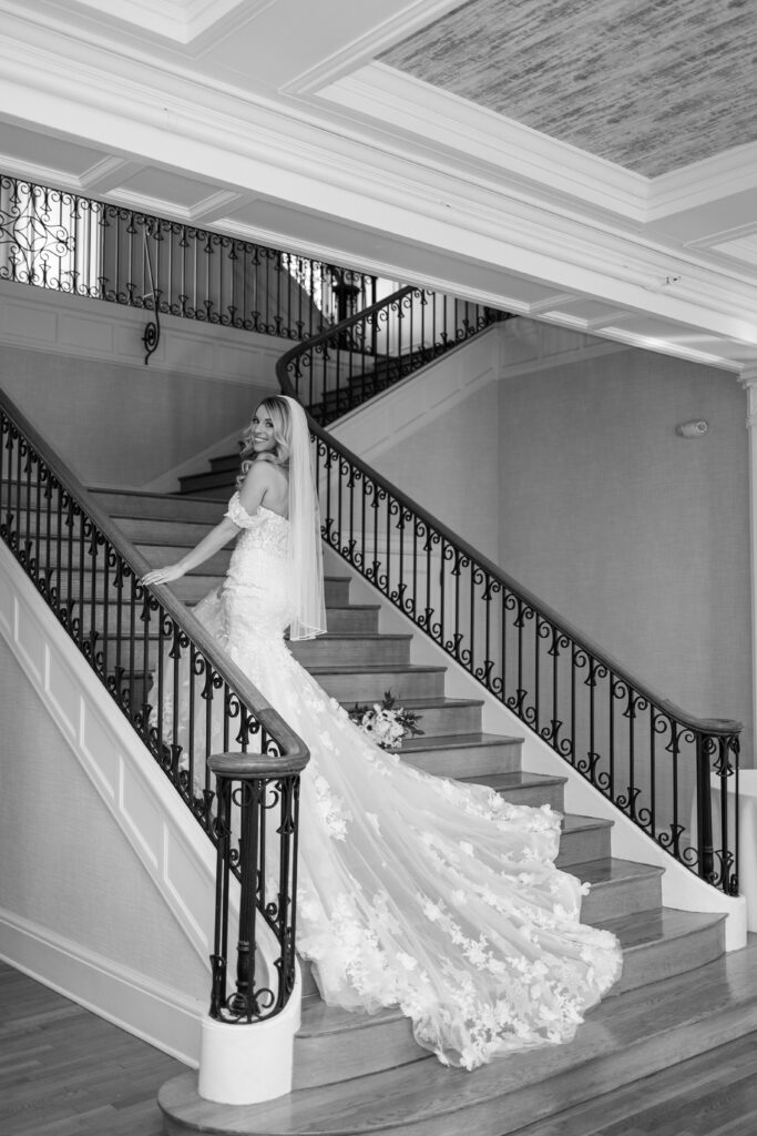 The bride walking up the stairs at King Mansion with her long train flowing behind her.