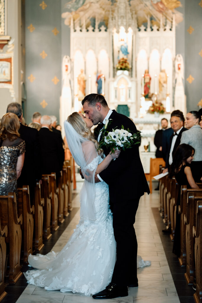 Bride and groom kissing at the end of the aisle. 