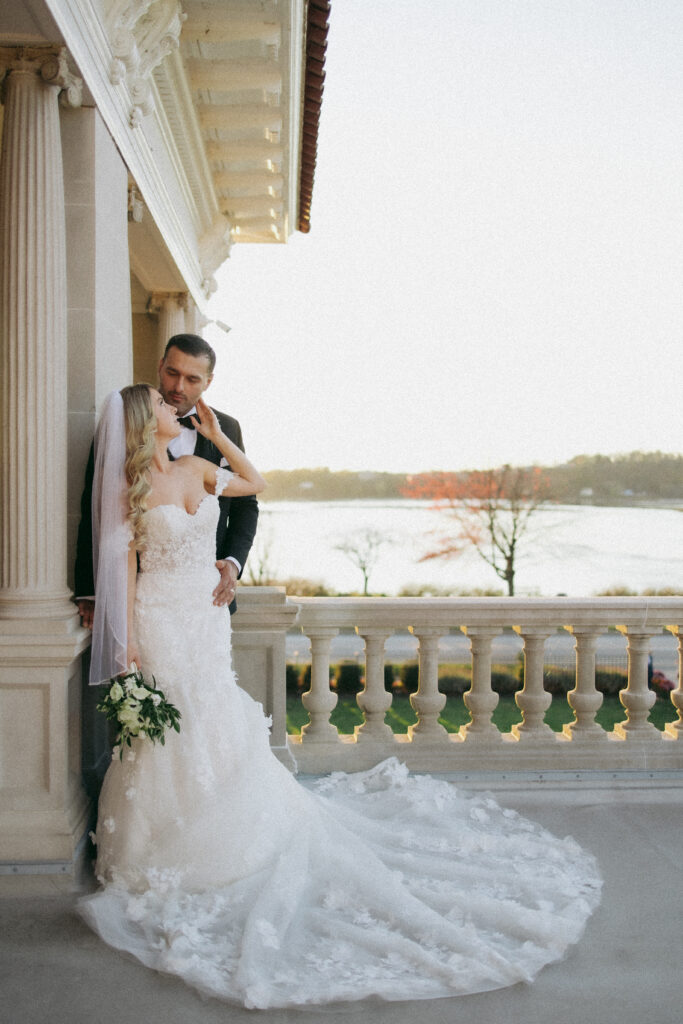 Newlyweds posing for elegant wedding photos at King Mansion on the terrance overlooking the large river.