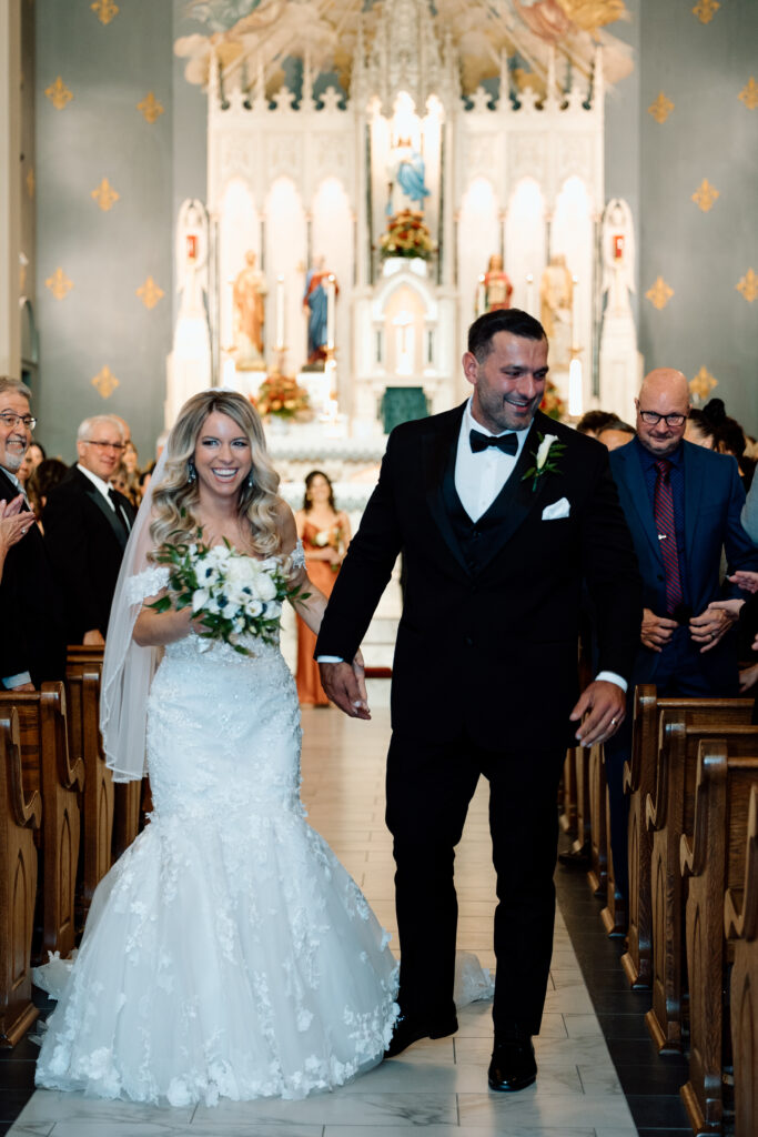 Newlywed couple laughing as they exit their wedding ceremony. 