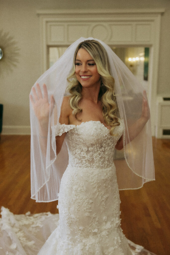 Bride smiling while touching her veil.