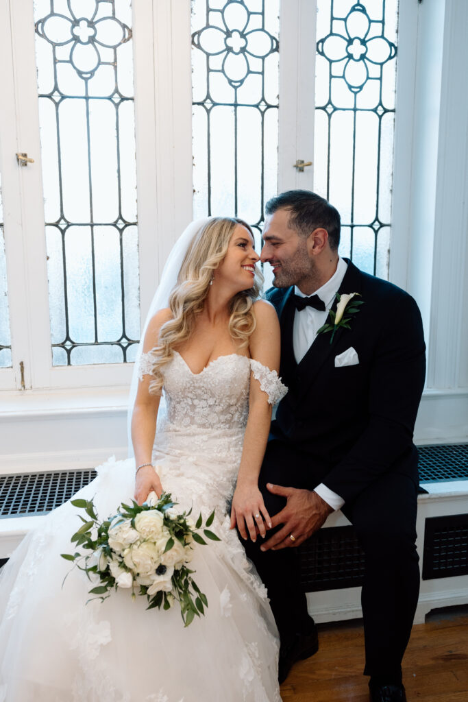 Bride and groom about to kiss by a window at their wedding venue. 