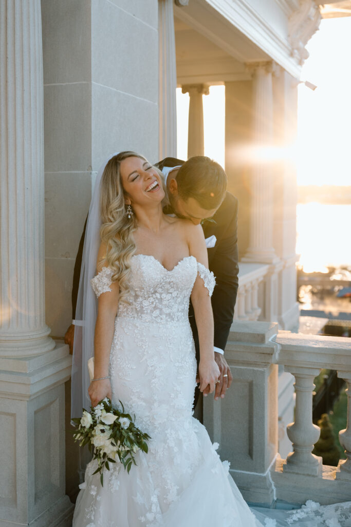 Groom kissing his bride's shoulder as the bride laughs. 