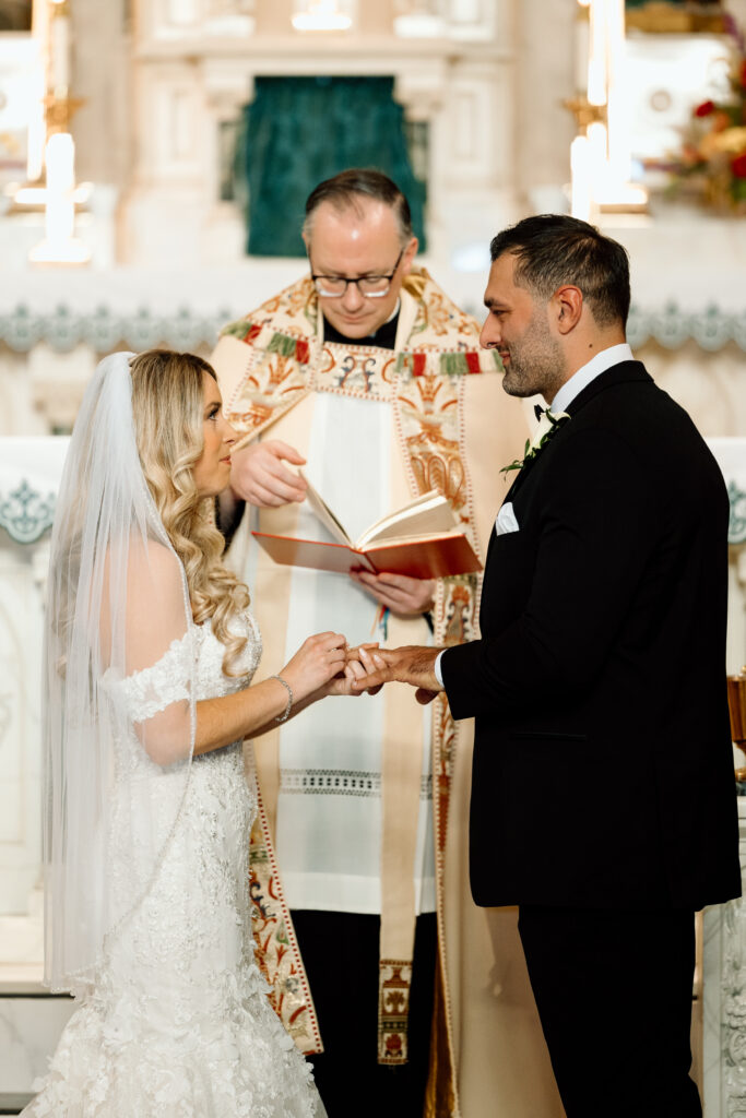 Bride and groom sharing rings at the altar.