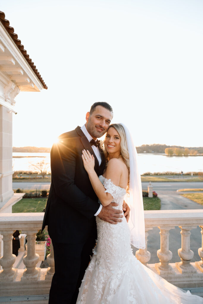 The newlyweds smiling for their elegant wedding photos with the river in the background.