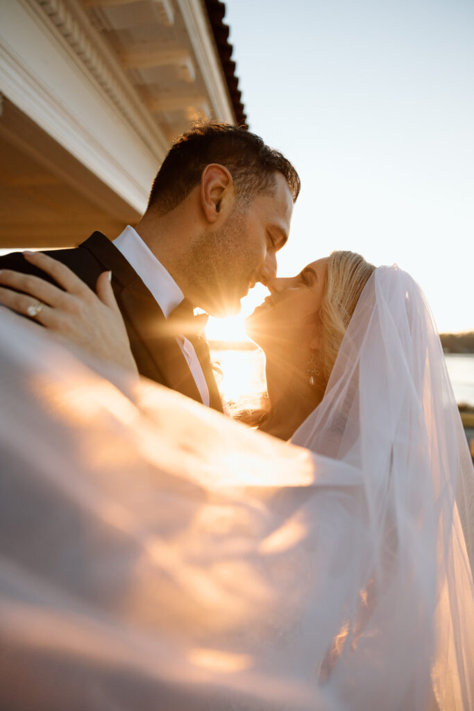 Bride and groom about to kiss with the sun shining in-between them. 