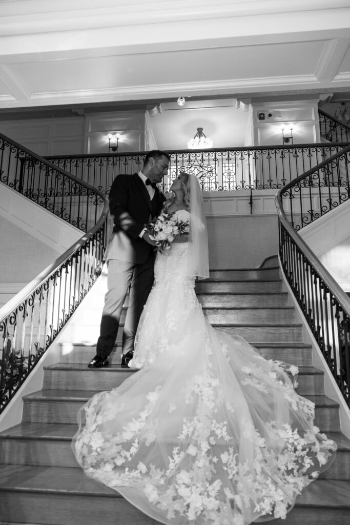 Bride and groom posing on the staircase at their wedding venue.