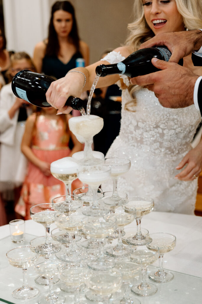 Close up of bride pouring champagne into their champagne tower. 