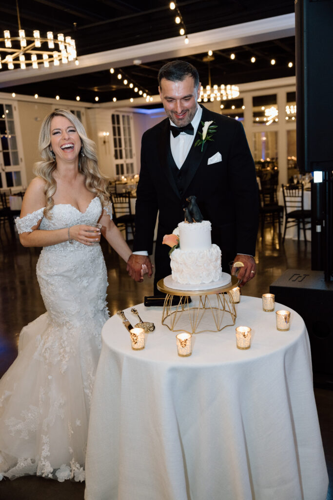 Newlyweds smiling while looking at their wedding cake.