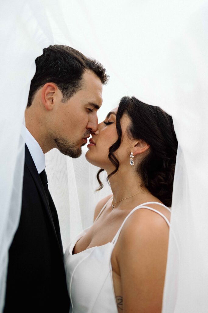 Bride and groom about to kiss under her veil. 