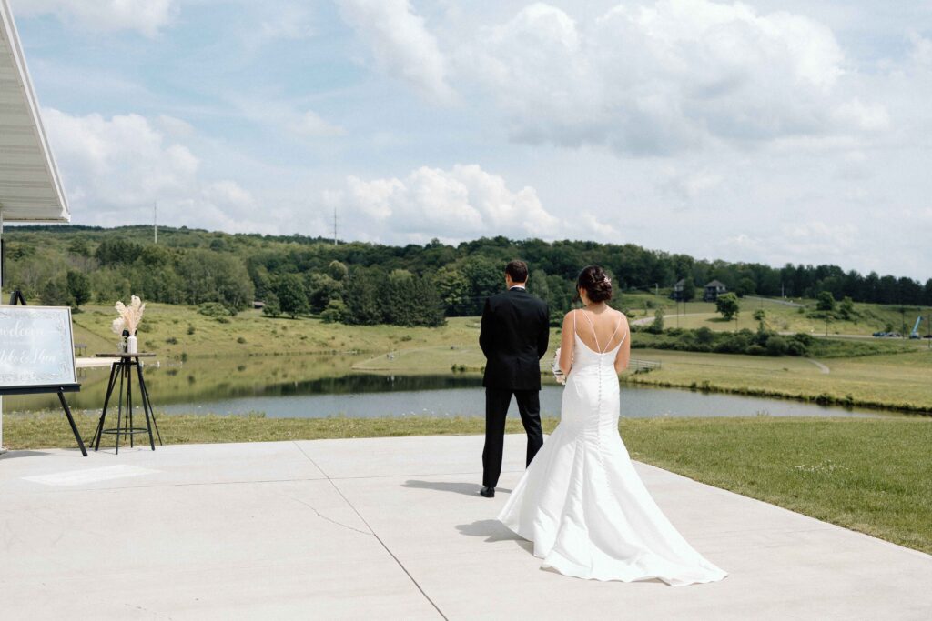 Groom with his back to the bride about to have a first look overlooking the lake at The Lookout at Hope Lake.