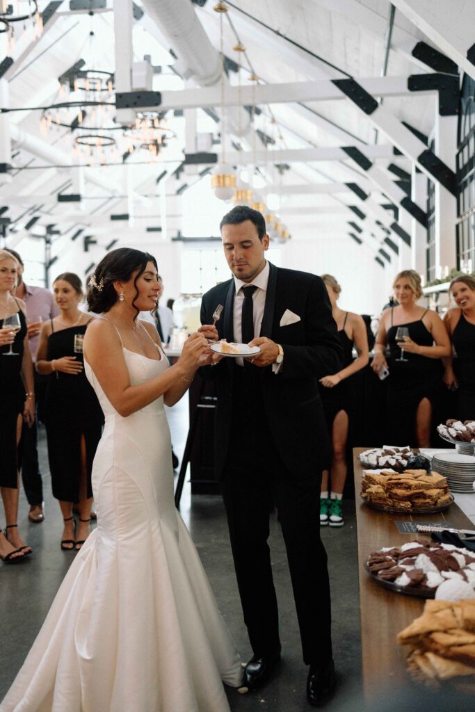 Newlyweds enjoying cake and dessert at their black and white wedding reception. 