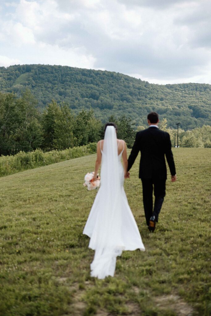 Bride and groom walking from behind with the mountains in the background at The Lookout at Hope Lake.