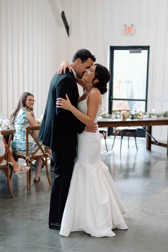 Bride and groom sharing their first dance. The bride is laughing. 