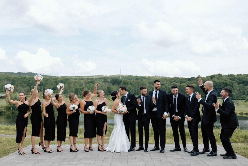 Wedding party cheering as the bride and groom kiss. 