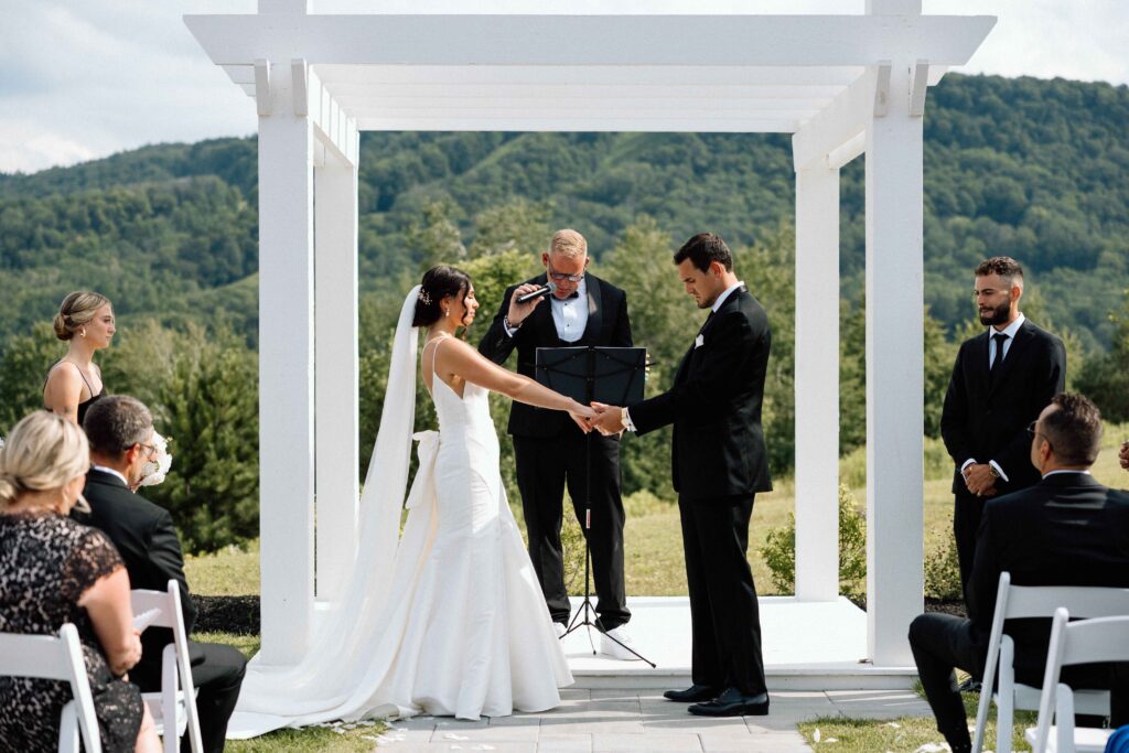 Bride and groom holding hands during the wedding ceremony as the officiant prays. 