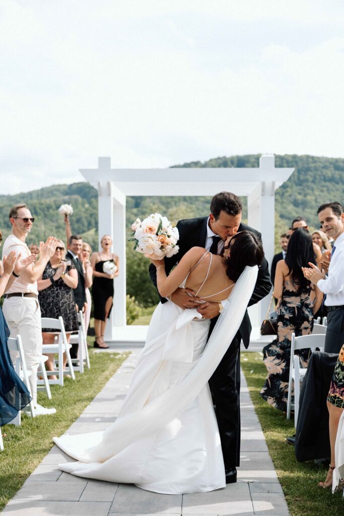 Newlyweds kissing at the end of the aisle at The Lookout at Hope Lake.