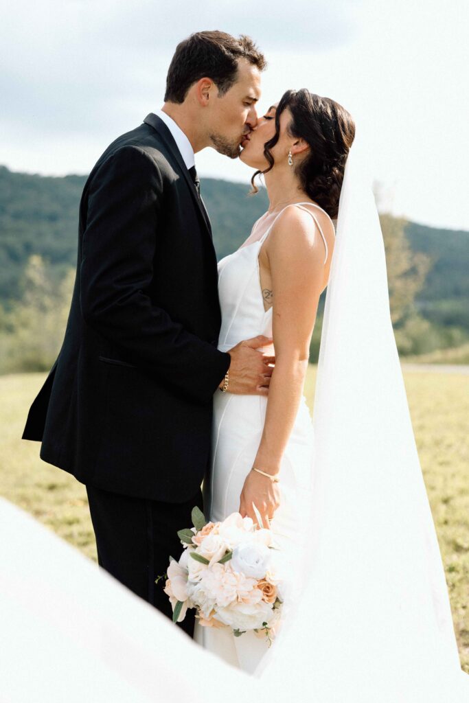 Newlyweds kissing during their wedding portraits at The Lookout at Hope Lake.