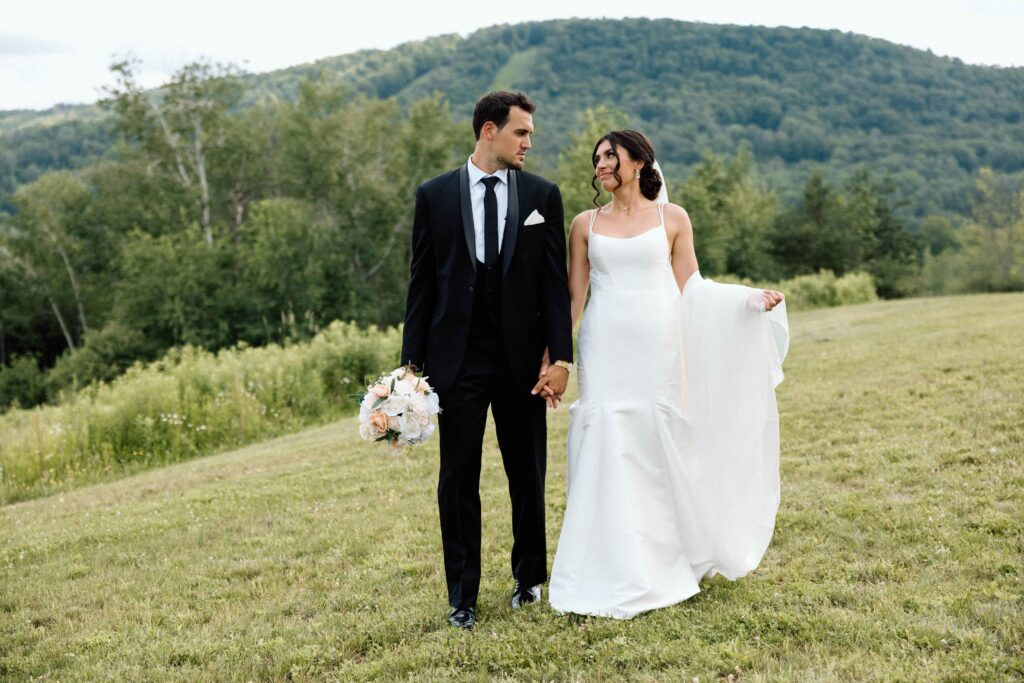 The newlyweds walking hand in hand at their wedding at The Lookout at Hope Lake.