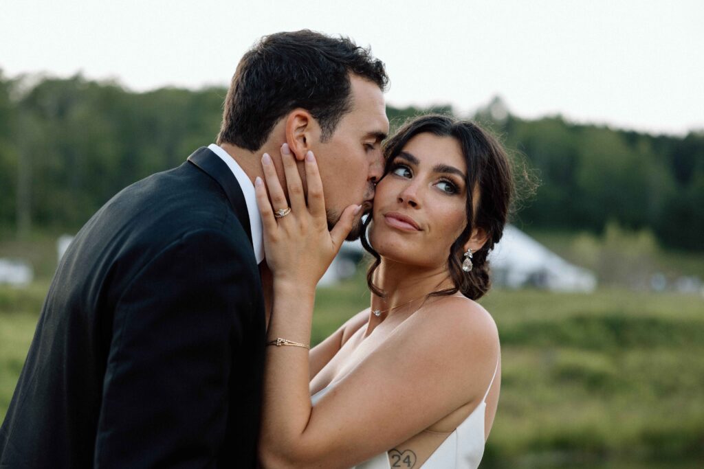 Groom kissing his bride's cheek.