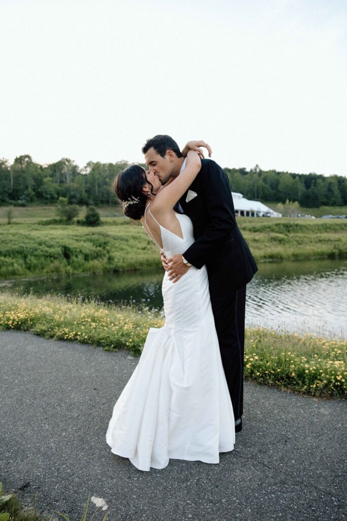 Bride and groom kissing by the lake.