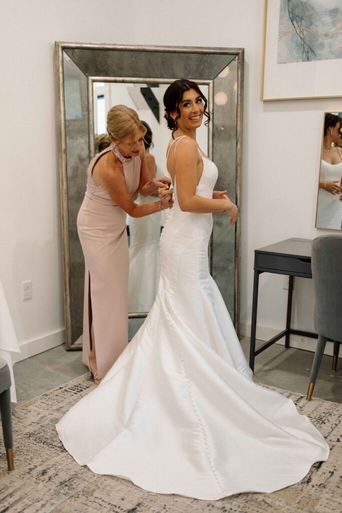 Bride's mother buttoning up her wedding dress. 